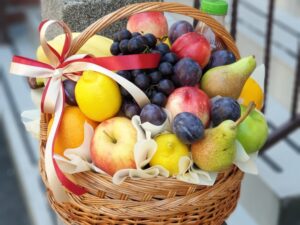 pletena voćna korpa puna svežeg voća. Jabuke banane, kruške, groždje, sljive, breskve i kvalitetan gusti sok od 100% voća